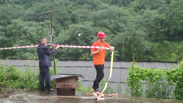 《警戒》。6月28日，綦江区石壕镇一处斜坡突发滑坡险情，重庆一三六地质队地灾驻守工程师邓森木（右）配合当地政府工作人员在现场处置，设置警戒范围。杜健摄