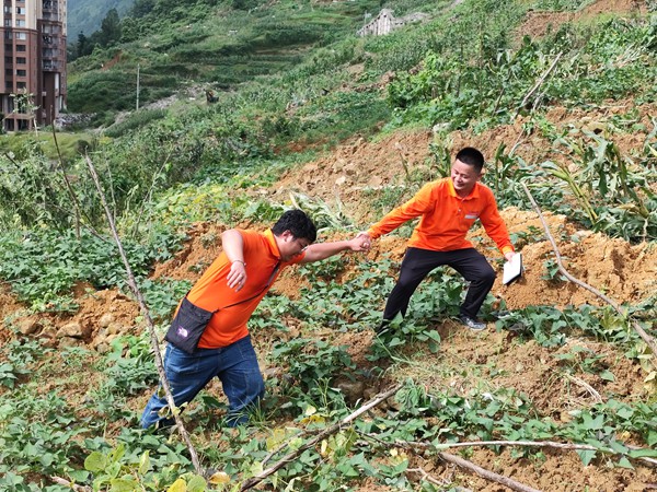 《跋涉》。6月29日，107地质队的驻守地质工程师陈虹洲在彭水巡查雨后的地灾点时深陷泥潭，同事王发英搭手拽他脱离“困境”。李明亮摄