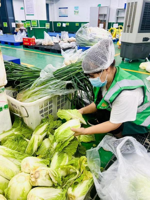 配送人員按照訂單精心挑選著各類新鮮的蔬果，確保每一份食材都符合質量標准。豐都實業供圖。