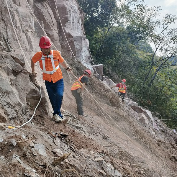 《排危除险》。8月8日，107地质队地质工程师万英（左一）在渝北区一处危岩排危抢险工程现场指导作业人员进行危岩清除工作。 彭张龙摄