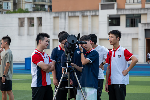 学生用望远镜观月。学校供图