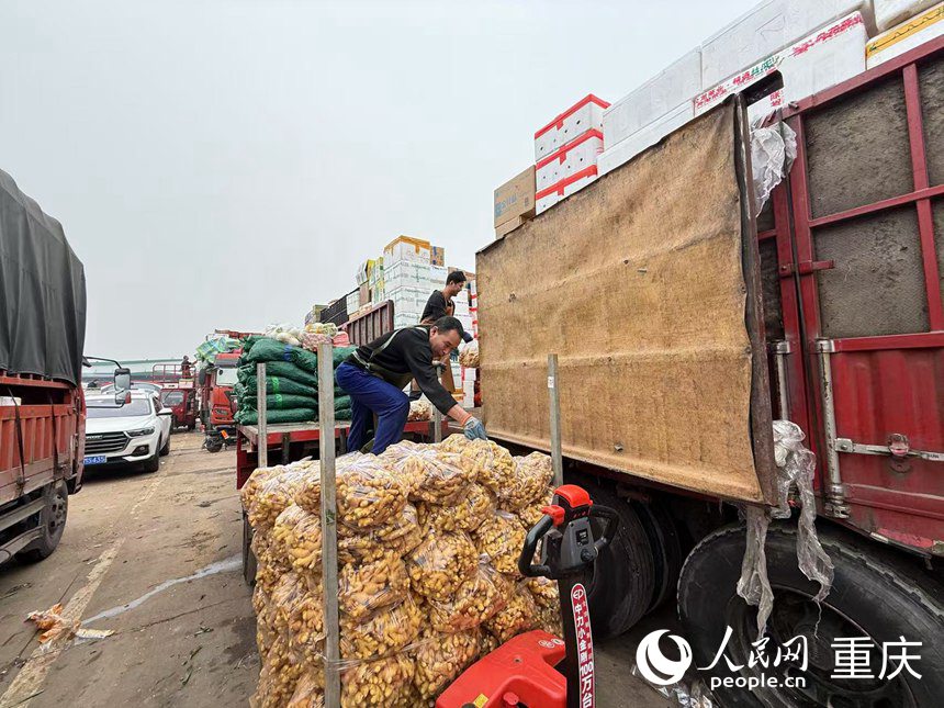 搬运工正将三轮车上的货物搬上货车。人民网记者 胡虹摄