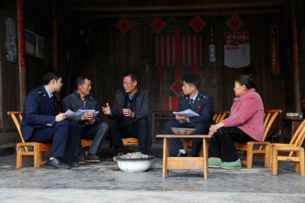 秀山县税务局派驻云隘村的第一书记陈夕才（左三），与一同前往的税务工作人员挨家挨户走访，为云隘村村民详细讲解医保等相关政策。张雯惠摄