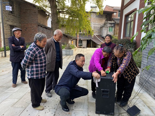 图为刘华（左四）为村民调试广场舞设备，笑声与音乐声交织成乡村新乐章。重庆移动供图