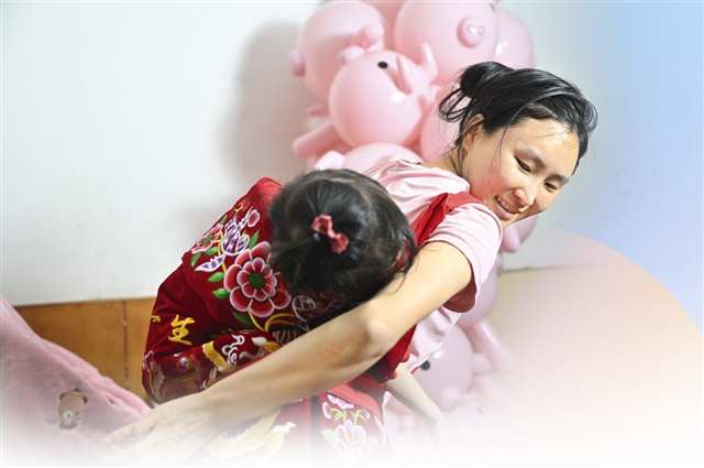 5月7日，渝中区上清寺学田湾，刘英笑着唱起儿歌轻拍背上的球球。记者 刘力 摄/视觉重庆
