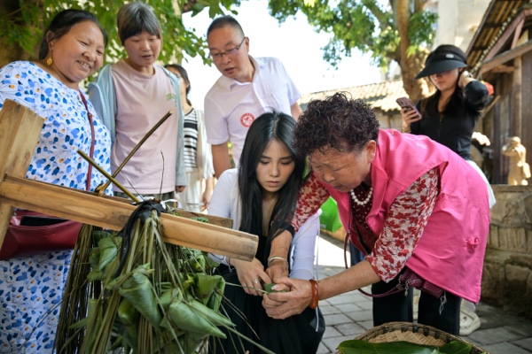 游客在當地居民的指導下包粽子。綦江區委宣傳部供圖