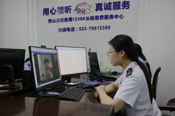 在秀山縣稅務局12366納稅繳費服務中心，稅務人員正通過虛擬窗口與企業辦稅人員視頻連線，辦理跨區域涉稅業務。張雯惠攝