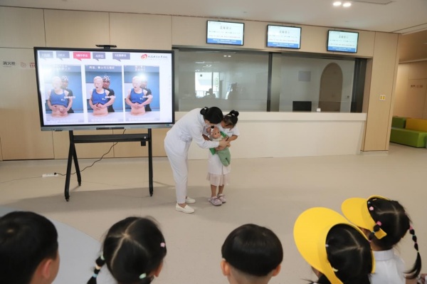 萌娃在医院工作人员的指导下学习海姆立克急救方法。赵海摄