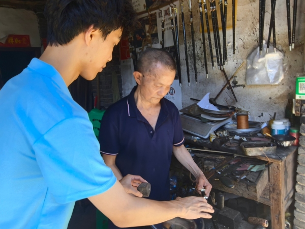 服務隊成員採訪手工木秤制作者王澤喜老人。重慶財經學院供圖