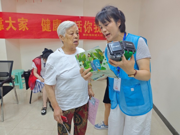 工作人员通过垃圾分类彩页、模型等向老年人讲解垃圾分类知识。吕丽珊摄
