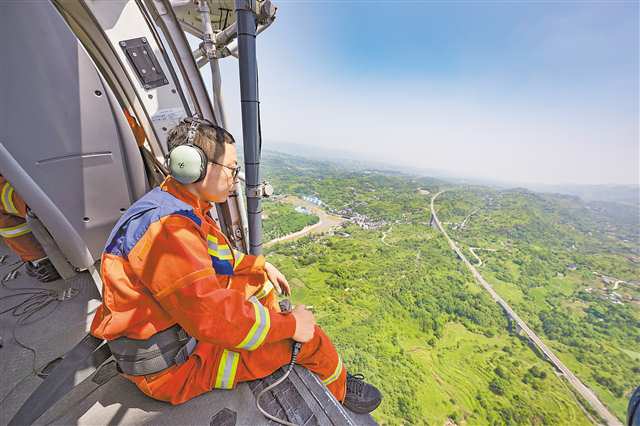 7月15日，渝北龍興，市航空應急救援總隊隊員在直升機上巡查。