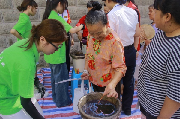 践行团成员引导居民体验非遗活动。重庆电力高等专科学校供图