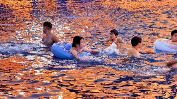 游客在晚霞映照的水面戏水。景区供图