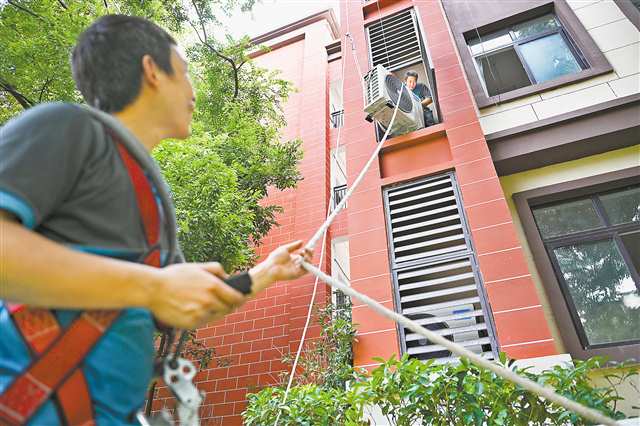 8月5日，南坪实验金科小学，工人正在吊装空调外机。近日，南岸区启动“清凉工程”，将为58所中小学校统一安装空调共3650台。记者 谢智强 摄/视觉重庆