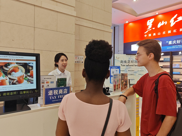 在解放碑的重庆环球金融中心离境退税服务台,工作人员为来自俄罗斯和西非多哥的游客介绍离境退税“即买即退”服务。徐佑君摄