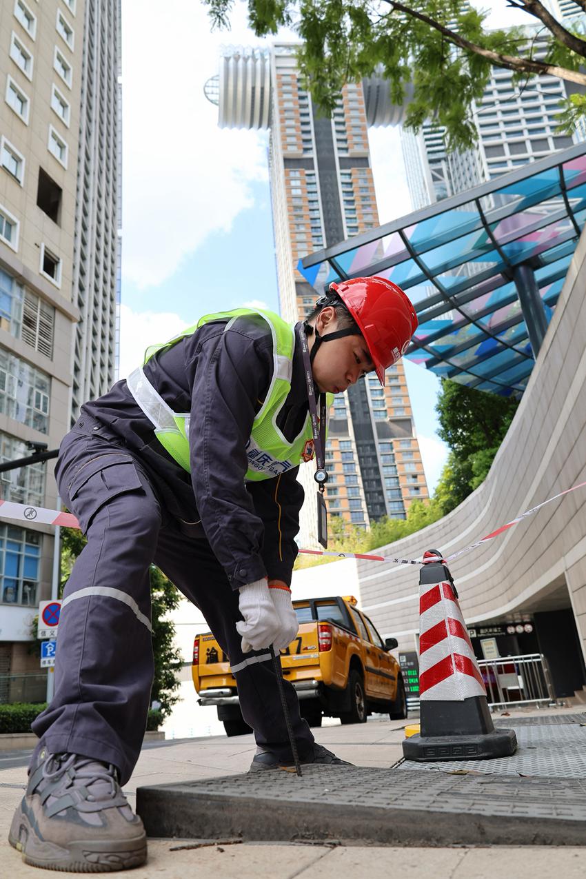 渝中區來福士廣場附近，“紅岩燃小兵”使用專用工具打開閥井蓋，准備進行燃氣濃度檢測。重慶燃氣集團供圖