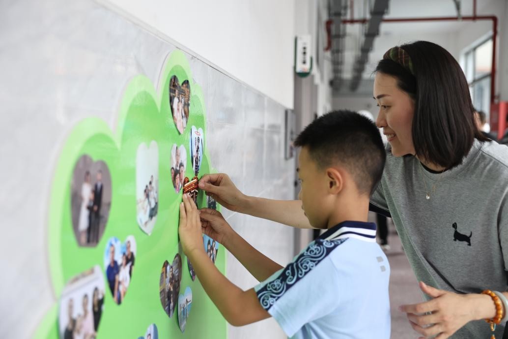 勉仁小学一年级新生在成长树上贴全家福。晏滢滢摄