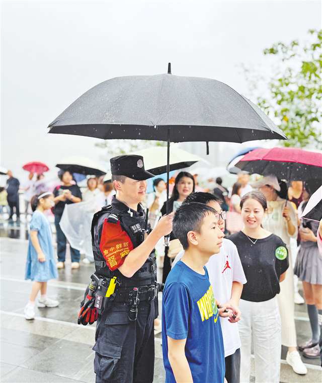 十月二日，渝中区李子坝观景平台，突然下起雨来，正在执勤的群防督察队队员暖心地为游客撑伞挡雨。（受访者供图）