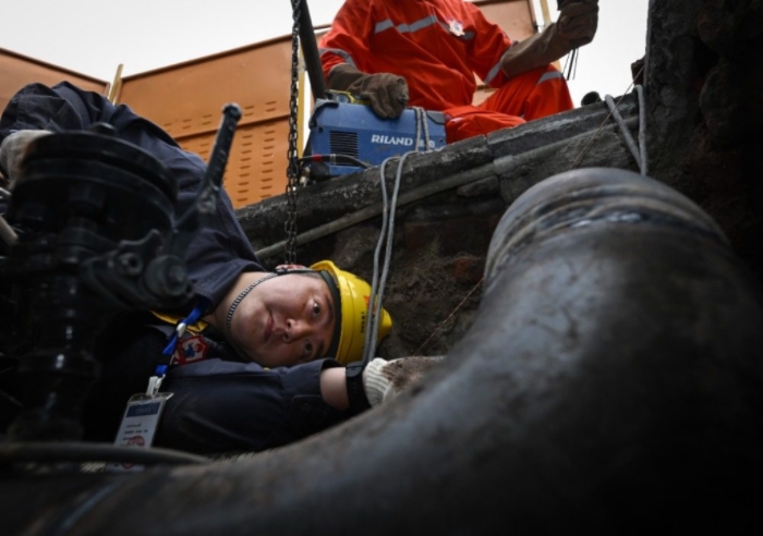 近日，大渡口区钢花路，抢险班班长刘瀚林在阀井作业坑里检查焊口焊接质量。记者 张锦辉 摄/视觉重庆