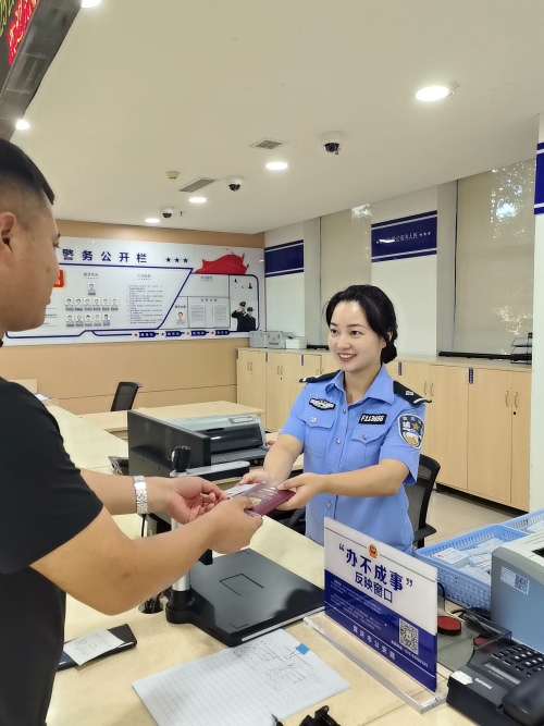 王先生从辅警手中接过身份证和港澳通行证。南岸区公安分局供图