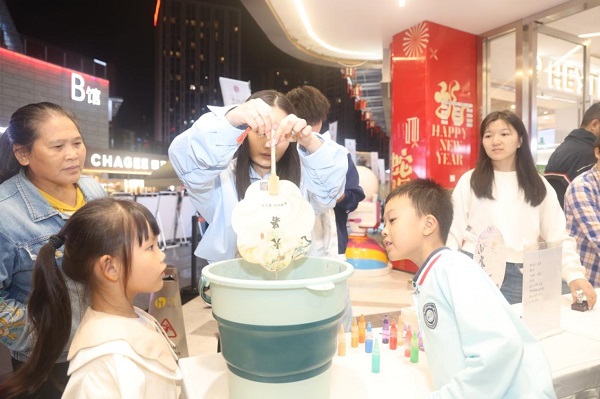 年轻市民用印有中医药文化知识的纸扇体验漆扇制作。曾英豪摄