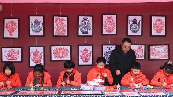 菜市街小学学生正在老师的指导下剪纸。李波摄