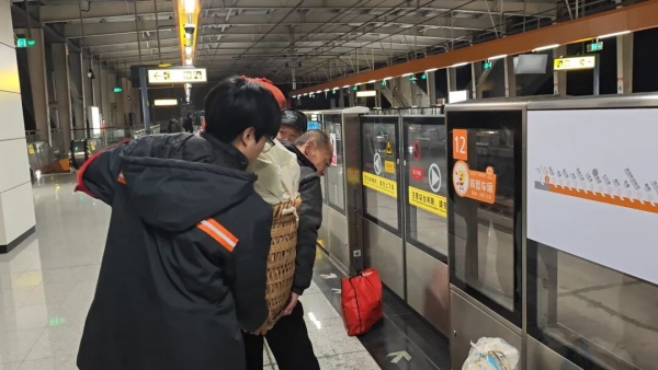 工作人員幫助乘客抬起背簍。重慶軌道四號線公司供圖