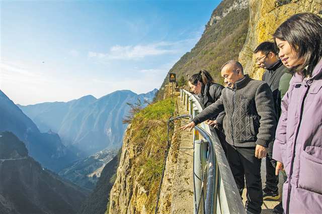 　巫山县竹贤乡下庄村“天路”上，毛相林给年轻人讲述修路的往事。（资料图片）记者 尹诗语 摄/视觉重庆