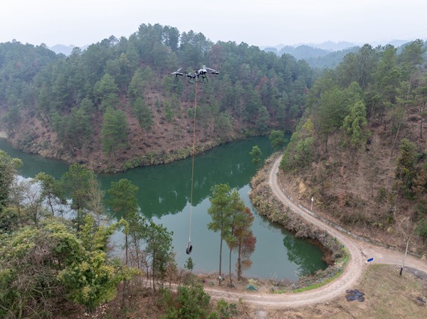 学员在供销社农技工作人员的指导下操控农用无人机在河道与山坡间灵活进行吊运作业。罗川摄