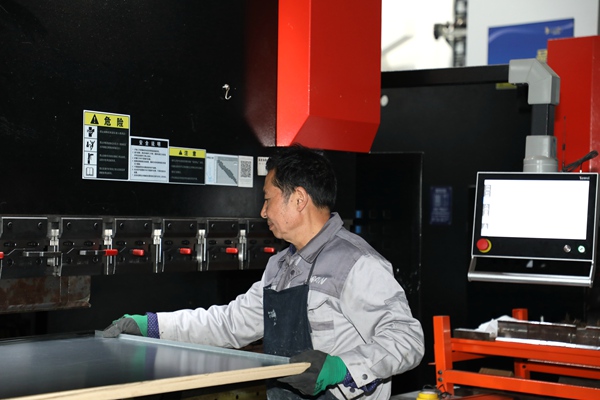 在數控折彎機前，歐偌醫療的談安建師傅專注操作，精准把控板材加工精度。兩江協同創新區供圖