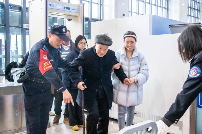 巫山站安检口，高要武搀扶行动不便的老年旅客通过安检。胡勇摄