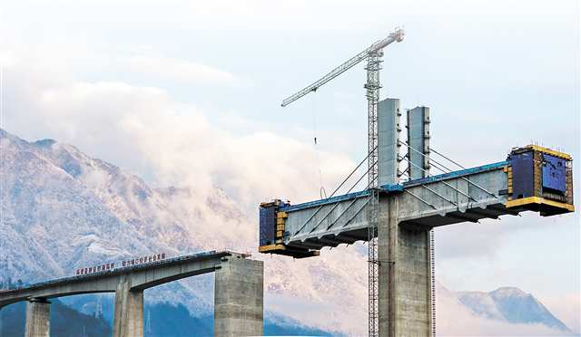 1月22日，任河特大桥建设现场，远处覆盖着白雪的山脉被晚霞染成粉色（无人机照片）。本组图片由记者李雨恒摄/视觉重庆
