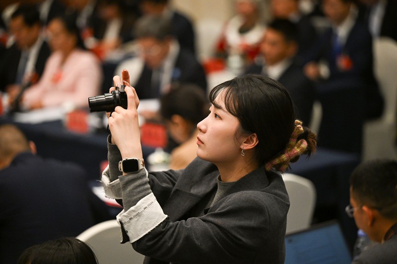3月6日上午,十四屆全國人大四次會議重慶代表團舉行開放團組會議,一位女記者起身舉起相機,在密集的人群中捕捉關鍵瞬間。記者 蘇思 攝