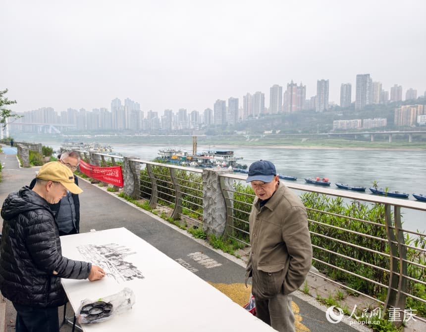 南滨路步道旁，老人用墨笔勾勒对岸的城市轮廓。人民网 陈琦摄
