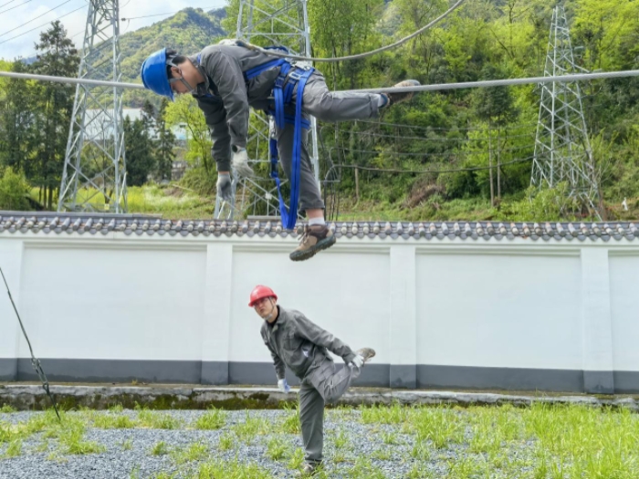 冉洪位（下）在实训场地指导青年员工冉青云坐线技巧。国网城口供电公司供图