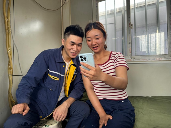 工地宿舍里，陈先锋、郭梦娜夫妻通过手机与留守在宜宾老家的孩子视频聊天。李婷摄。