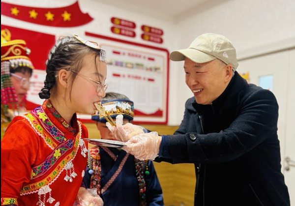 校党支部书记任红卒在活动中与学生共品饺子。校方供图