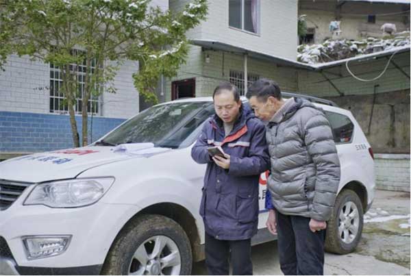 张友军（左）为农户普及金融保险知识。人保财险重庆分公司供图