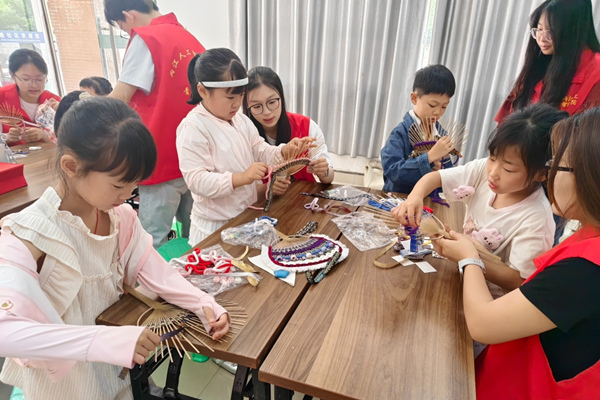 志愿者指导孩子们制作壮锦扇。重庆理工大学供图