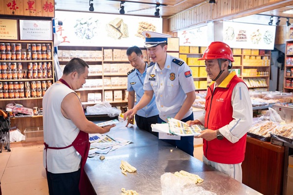 工作人员在古镇沿街商铺现场排查，向店主指出用电安全隐患。屈思芬摄
