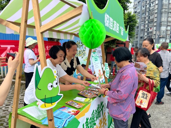 公益摊位向居民发放政策宣传资料。童瑶摄