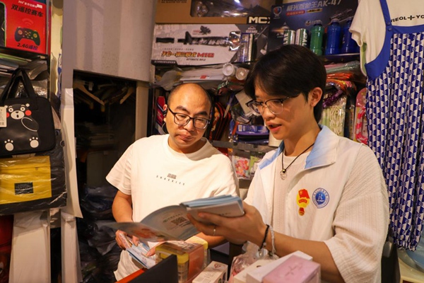 志愿者给商户进行反诈宣传。重庆财经学院供图