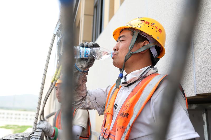 一名施工人员在工作间隙补充水分（资料图）。新华社记者 陈斌 摄