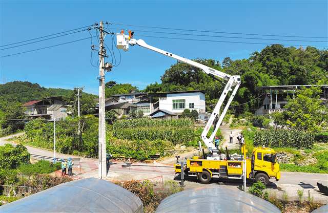 7月14日，沙坪壩中梁山片區，一台雙臂帶電作業機器人搭乘斗臂車升至十余米高空開始作業（無人機照片）。