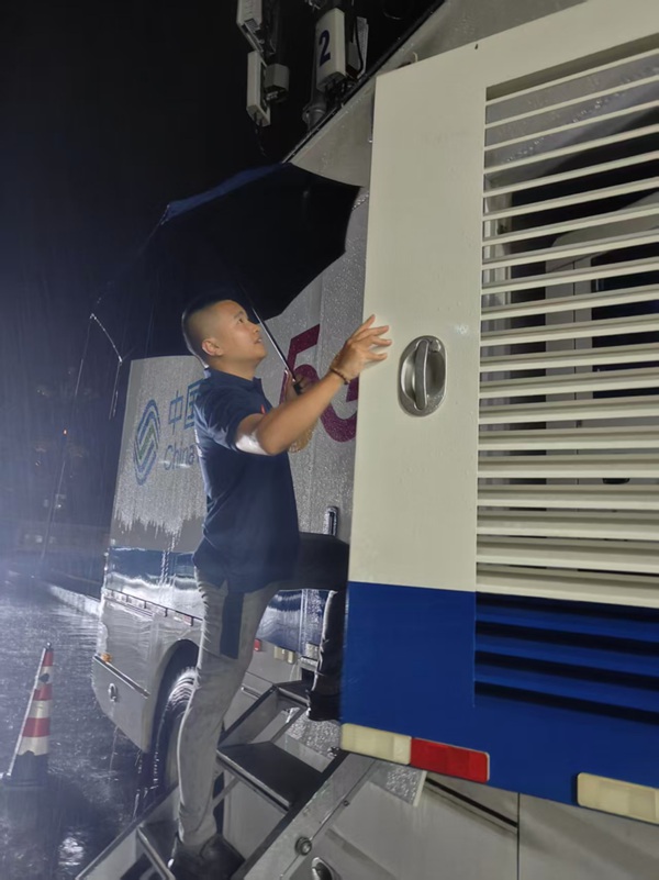 暴雨中,保障人员坚守在应急通信车旁。中国移动重庆公司供图