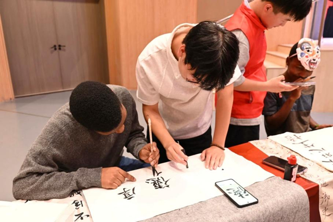 传承团成员指导国际学生体验书法。校方供图