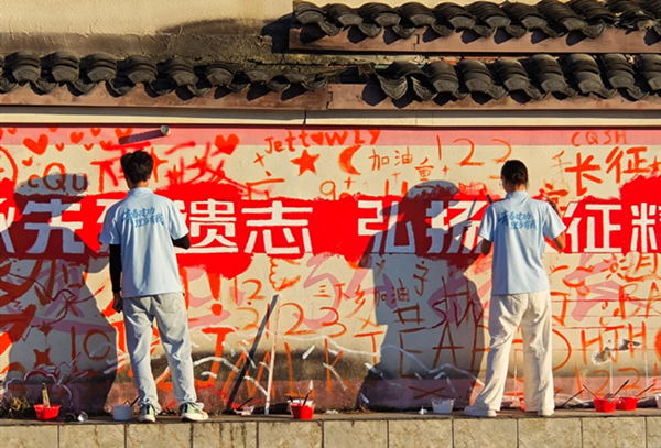 实践团成员执笔勾勒红色墙绘。校方供图