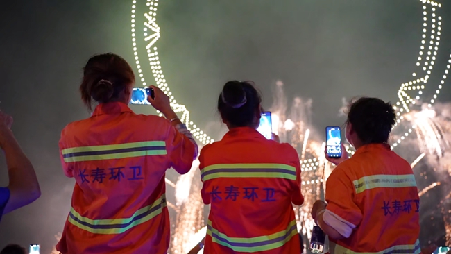 环卫工人举起手机拍下漫天烟花。