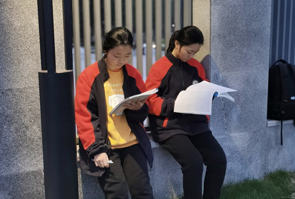 姐妹俩在校门口看书。受访者供图