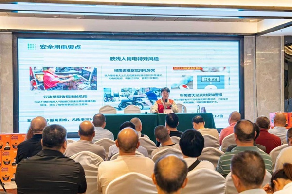 国网重庆长寿供电公司志愿者为现场肢残人士讲授安全用电知识。袁佳摄